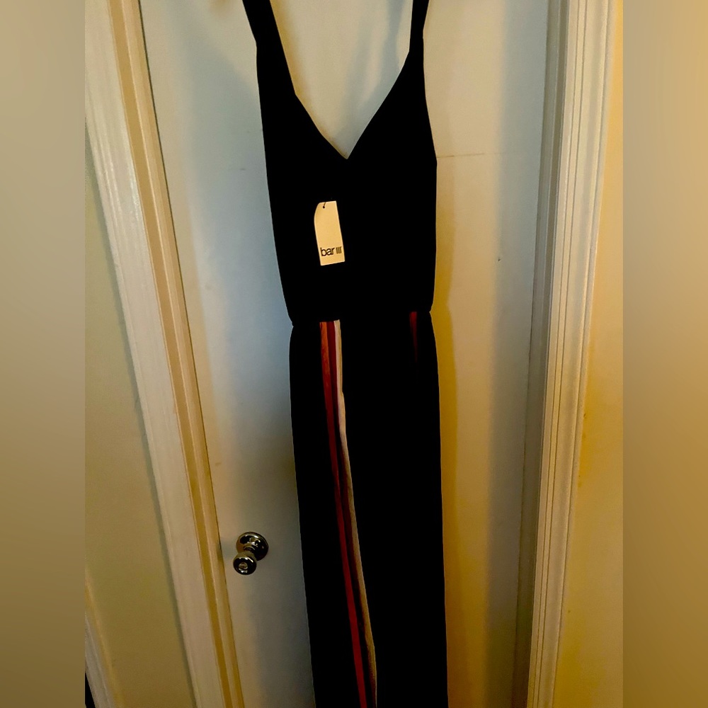 Black jumpsuit with purple, yellow and white pinstripe down wide leg with slits.